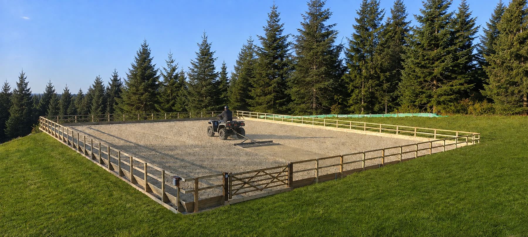 An arena being harrowed, a quad bike towing a leveller across a freshly worked surface
