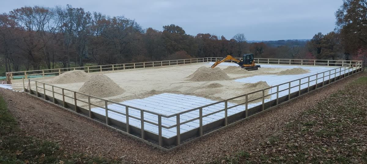 Heaps of arena surface material waiting to be spread over a membrane-covered base